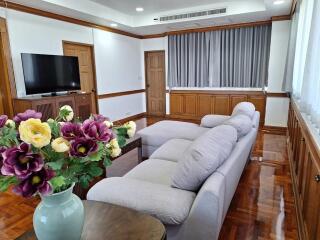 Spacious living room with large sofa, hardwood floors, and modern wooden paneling