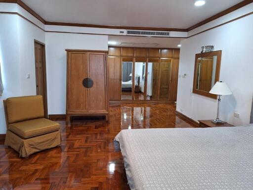 Spacious bedroom interior with polished hardwood floors, large wardrobe, and ample natural light