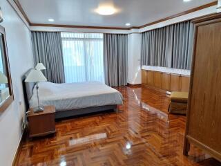 Spacious bedroom with wooden flooring and large windows