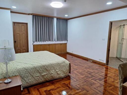 Spacious bedroom with wooden flooring and modern lighting