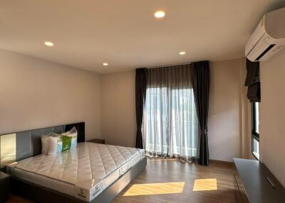 Spacious bedroom with a large bed, hardwood floors and ample natural light