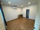 Spacious unfurnished bedroom with air conditioning and hardwood flooring