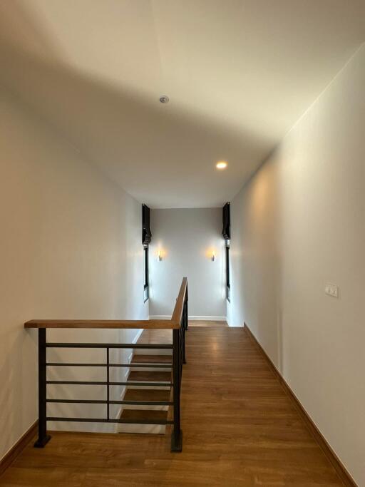 Bright hallway with wooden flooring and wall sconces