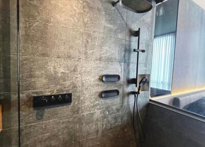 Modern bathroom with dark tiles and wall-mounted shower