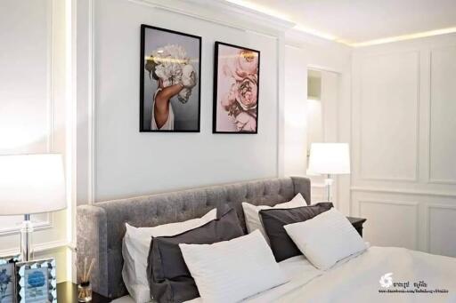 Elegantly decorated modern bedroom with framed wall art and plush bedding