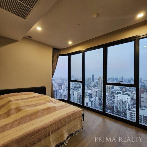 Cozy bedroom with large windows overlooking the city