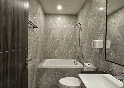 Modern bathroom with marble tiles, bathtub, and sleek fixtures