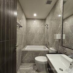 Modern bathroom with marble tiles, bathtub, and sleek fixtures