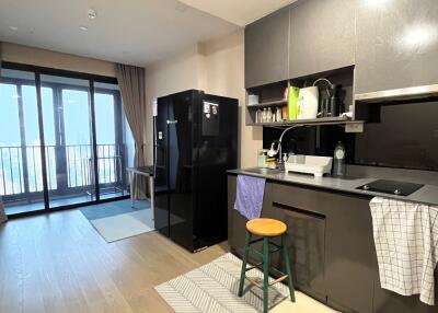 Modern kitchen with black appliances and balcony access in a city apartment