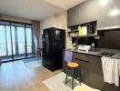 Modern kitchen with black appliances and balcony access in a city apartment