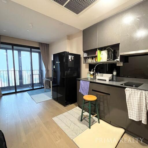 Modern kitchen with black appliances and balcony access in a city apartment