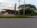 Exterior view of a building near the road taken at twilight with visible signage and vegetation