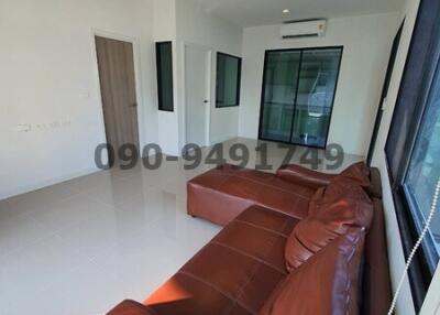 Spacious living room with brown leather sofa and ample natural light