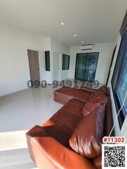 Spacious living room with brown leather sofa and ample natural light