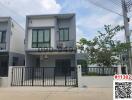 Modern two-story house with a gray and white exterior and fence