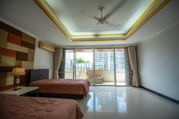 Spacious bedroom with two beds, ample lighting, and balcony access