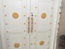 Ornate white double door with golden details and decorations
