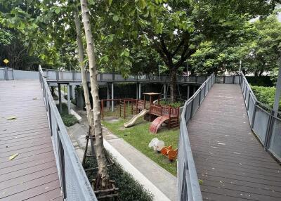 Wooden deck pathway with benches and greenery in an outdoor apartment common area