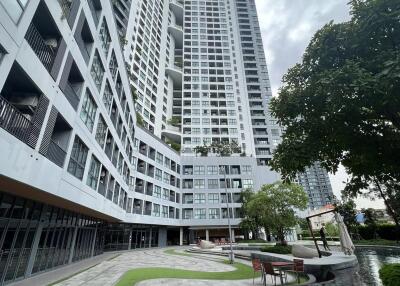 Modern high-rise residential building with landscaped garden and walking paths