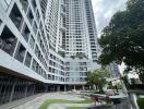 Modern high-rise residential building with landscaped garden and walking paths