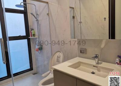 Modern bathroom interior with marble tiles, shower, and sink
