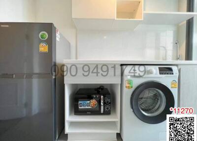 Modern kitchen with appliances including refrigerator and washing machine