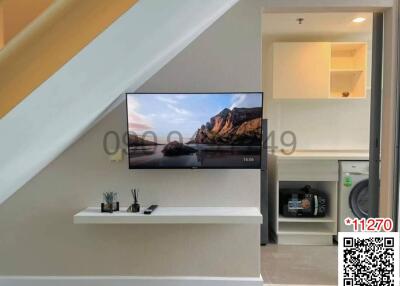 Modern living area with mounted television and adjacent kitchenette