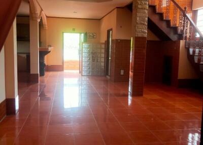 Spacious living room with terracotta tiles and open staircase