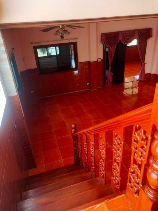 Spacious living room with red tiled floor and staircase