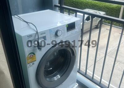 Washing machine on an apartment balcony with view of neighboring buildings