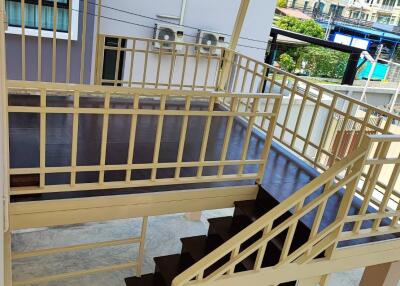 Spacious balcony with wooden railing and exterior staircase