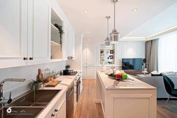 Modern kitchen with integrated living space featuring wooden floors, white cabinetry, and stainless steel appliances