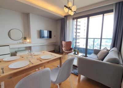 Modern living room with open kitchen, dining area, and comfortable seating by the window