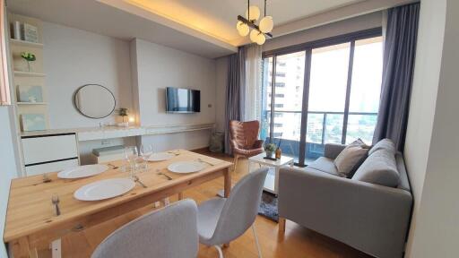 Modern living room with open kitchen, dining area, and comfortable seating by the window