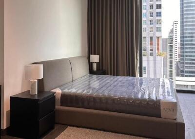 Modern bedroom with a large bed and city view through floor-to-ceiling windows