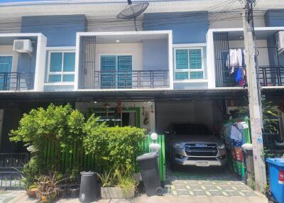 Modern townhouse with blue shutters, car parked in front, and small garden