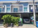 Modern townhouse with blue shutters, car parked in front, and small garden