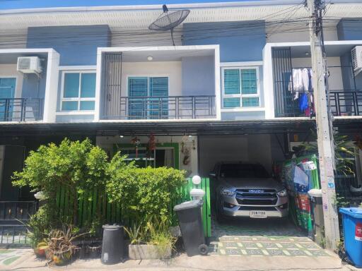 Modern townhouse with blue shutters, car parked in front, and small garden