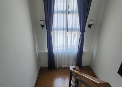Staircase landing with wooden floor and window dressed with blue curtains