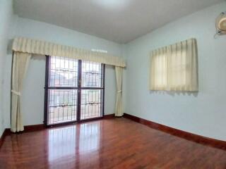 Spacious bedroom with large windows and hardwood floors