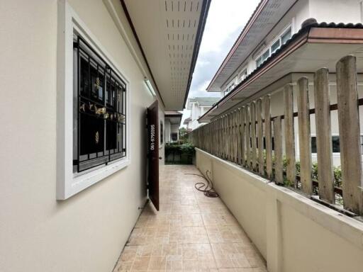 Narrow outdoor passageway with tiled floor and fenced boundary