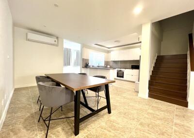 Spacious open plan living room with dining area, modern kitchen, and staircase