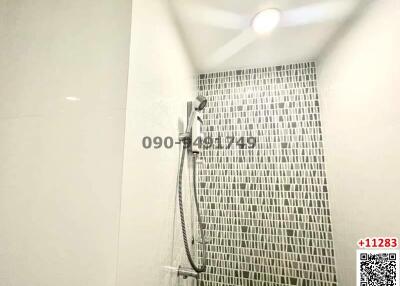 Modern bathroom with a wall-mounted shower and decorative mosaic tiles