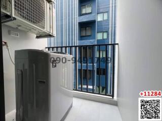 Compact balcony with blue building view and outdoor unit of an air conditioner