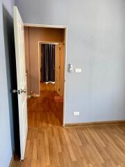 View of a residential hallway leading to additional rooms, featuring wooden flooring and neutral wall colors