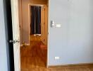 View of a residential hallway leading to additional rooms, featuring wooden flooring and neutral wall colors