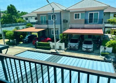 Balcony view overlooking neighboring residential homes with cars parked under carports on a sunny day