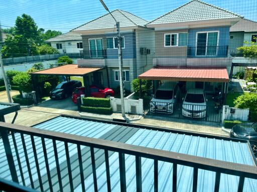 Balcony view overlooking neighboring residential homes with cars parked under carports on a sunny day