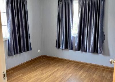 Empty bedroom with hardwood floors and curtains