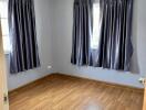 Empty bedroom with hardwood floors and curtains